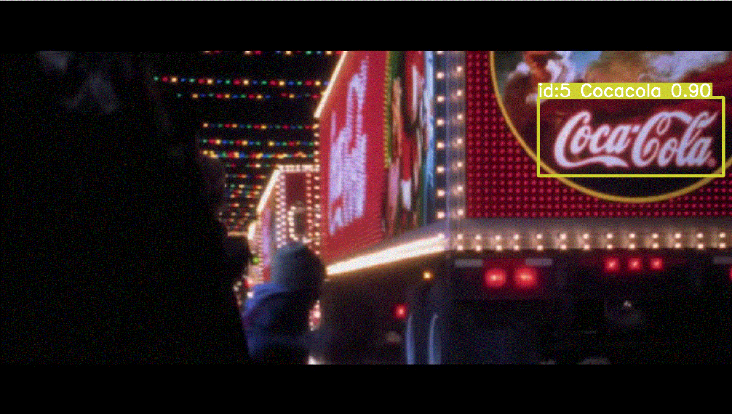 YOLOv8 tracking the Coca-Cola logo on the back of the lit-up holiday truck at night, with a labeled box and a confidence score of about 0.88